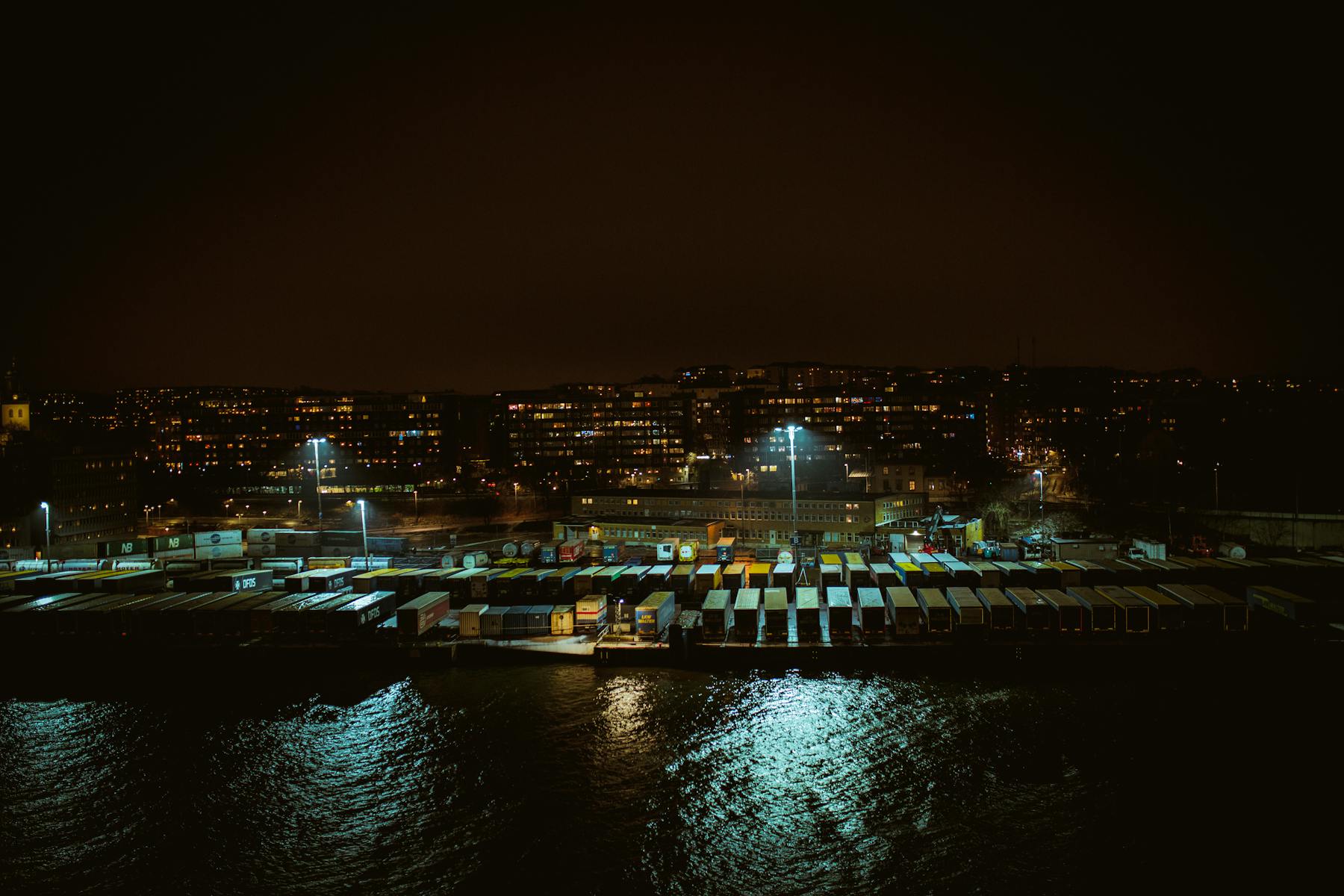 Aerial view of illuminated port, logistics, and container operations at night.